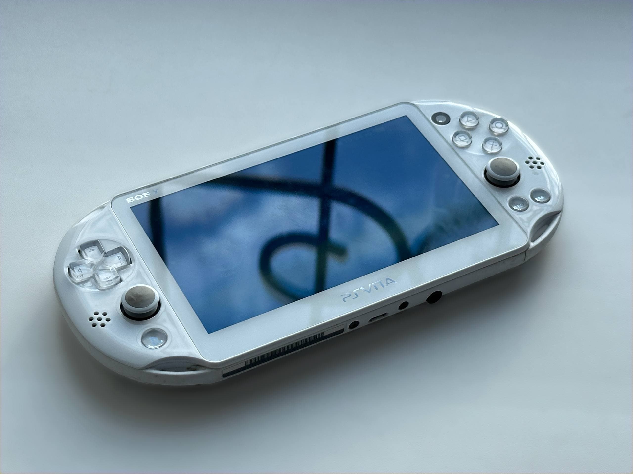Біла PS Vita 2000 Slim на світлому фоні